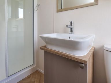 A bathroom sink with a faucet beside a shower enclosure at Willow Lodge in Whitby