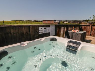 A hot tub with a table and champagne at Willow Lodge in Whitby