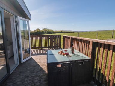 A deck with a table and chairs at Magnolia Lodge in Whitby
