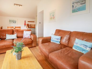 A living room with two brown leather sofas and a wooden coffee table with a potted plant at 3 Lake View in Lanreath