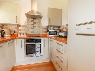 A kitchen with wooden countertops a stainless steel oven microwave toaster and cabinets at 3 Lake View in Lanreath