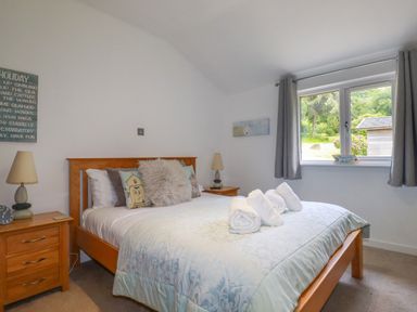 A bedroom with a wooden bed and bedside tables with lamps at 3 Lake View in Lanreath