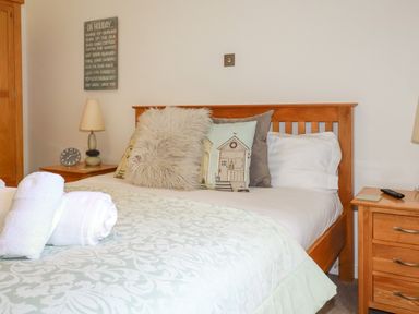 A bedroom with a wooden bed and bedside tables with lamps and a clock at 3 Lake View in Lanreath