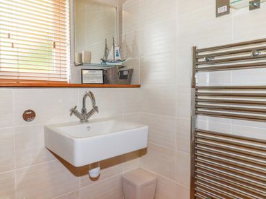 A bathroom sink with a faucet next to a window with blinds and a towel radiator at 3 Lake View in Lanreath