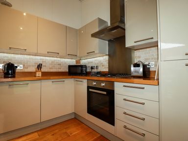A kitchen with beige cabinets wooden countertops a stove oven microwave toaster and kettle at 1 Hedgerows in Lanreath