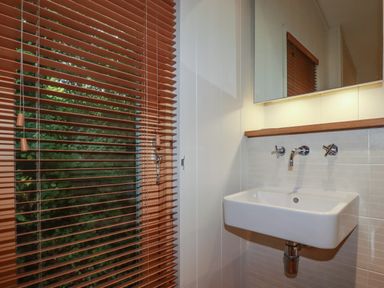 A bathroom with a wall-mounted sink and wooden blinds covering a window at 1 Hedgerows in Lanreath