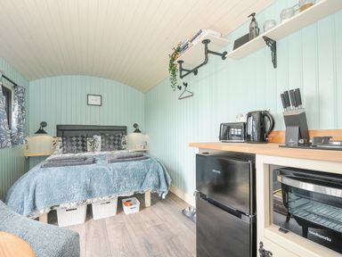 A bedroom with a double bed and bedside lamps beside a kitchen area with a fridge toaster kettle and knife set at Bracken Broad Langdon near Wainhouse Corner