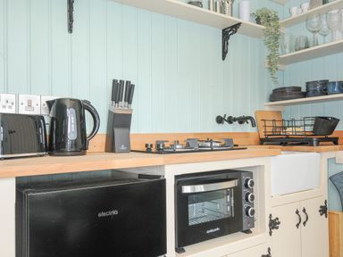 A kitchen counter with a toaster kettle knife block stove mini oven and open shelves with dishes at Bracken Broad Langdon near Wainhouse Corner