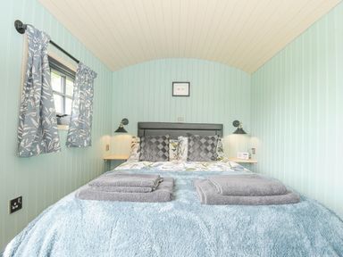 A bedroom with a double bed folded towels and floral curtains at Bracken Broad Langdon near Wainhouse Corner