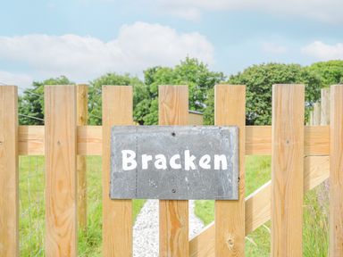 A wooden fence with a sign reading Bracken and a gravel path behind the fence at Bracken in Broad Langdon near Wainhouse Corner