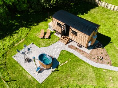 An aerial view of a tiny wooden cabin with two lounge chairs a small patio with a table and chairs and a hot tub at Bracken Broad Langdon near Wainhouse Corner