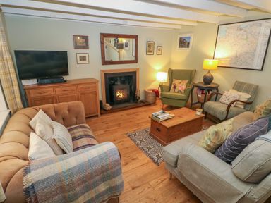A living room with sofas a wood stove a TV and armchairs at 2 Summerhill in Letterston