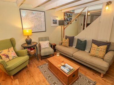 A living room with a green armchair and a beige sofa with patterned cushions at 2 Summerhill in Letterston