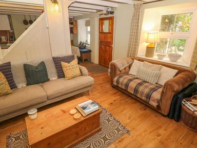 A living room with two sofas a wooden coffee table a table lamp and a wooden door at 2 Summerhill in Letterston
