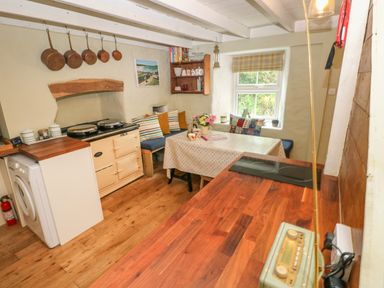 A kitchen with a washing machine cream stove wooden countertop and a dining table with cushions at 2 Summerhill in Letterston
