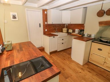 A kitchen with wooden countertops a white sink white cabinets and a cream stove at 2 Summerhill in Letterston