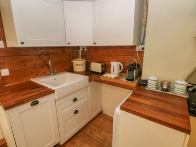A kitchen with white cabinets wooden countertops a white sink a bread container toaster kettle coffee machine and storage jars at 2 Summerhill Letterston