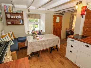 A kitchen with a wooden table covered with a cloth and a built in bench seating at 2 Summerhill in Letterston