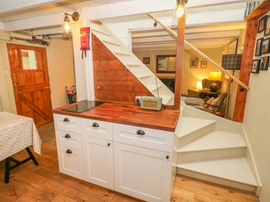 A kitchen area with white cabinets and wooden countertop next to white stairs and a wooden door at 2 Summerhill in Letterston