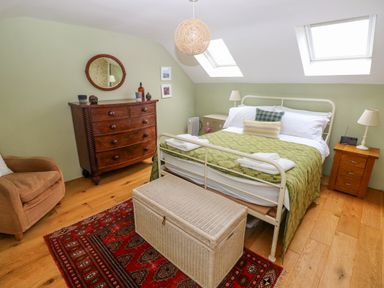 A bedroom with a bed a chest of drawers an armchair and skylights at 2 Summerhill in Letterston