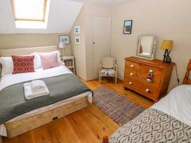 A bedroom with two beds a wooden dresser chair and skylight at 2 Summerhill in Letterston