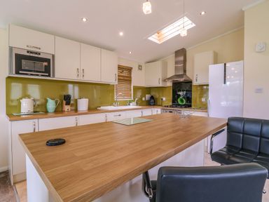 A kitchen with wooden countertops white cabinets and black chairs at Owls Retreat Lodge 11 Near Aldeburgh