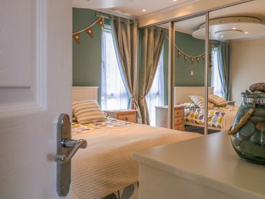 A bedroom with a bed striped pillow bedside tables curtains and a mirrored wardrobe at Owls Retreat Lodge 11 Near Aldeburgh