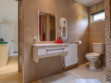 A bathroom with a toilet a vanity with a mirror a wall-mounted hair dryer and a window at Owls Retreat Lodge 11 Near Aldeburgh
