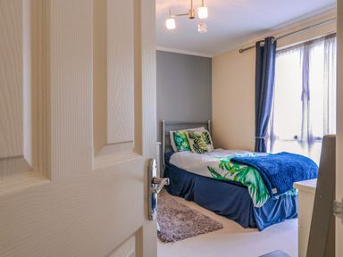 A bedroom with a single bed near a window with blue curtains at Owls Retreat Lodge 11 Near Aldeburgh