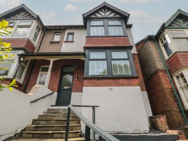 The front entrance of a two-story house with steps leading to a dark green door and large windows at Thirty Four By the Sea in Scarborough