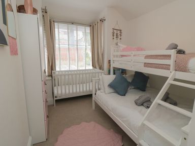 A bedroom with a white bunk bed a crib and a wardrobe at Thirty Four By the Sea in Scarborough