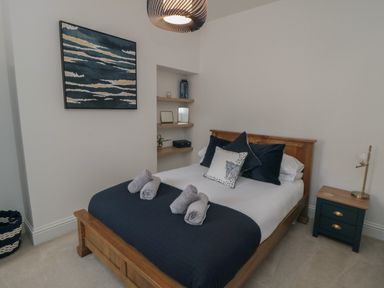 A bedroom with a wooden bed navy bedding bedside table and wall shelves at Thirty Four By the Sea Scarborough
