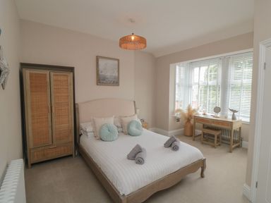 A bedroom with a bed, wardrobe, dressing table, window blinds, and a light fixture at Thirty Four By the Sea in Scarborough