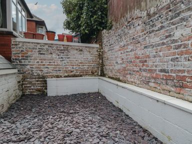 A small outdoor area with slate stones on the ground and brick walls with plant pots on top at Thirty Four By the Sea in Scarborough