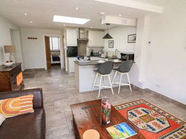 A kitchen with an island and two bar stools next to a living area with a sofa and a coffee table at 3 Palms in Preston Sands