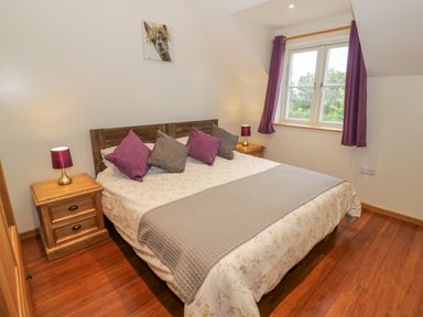 A bedroom with a double bed four pillows bedside tables with lamps a window and artwork at Lavender Cottage in Oxhill near Tysoe