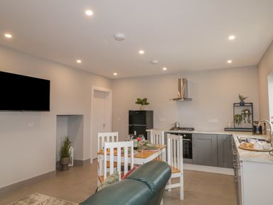 A kitchen and dining area with a dining table set for four and a black refrigerator at ARD NA GHAOITHE in Loughanure County Donegal
