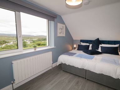 A bedroom with a bed and pillows next to a window overlooking a landscape at ARD NA GHAOITHE in Loughanure County Donegal