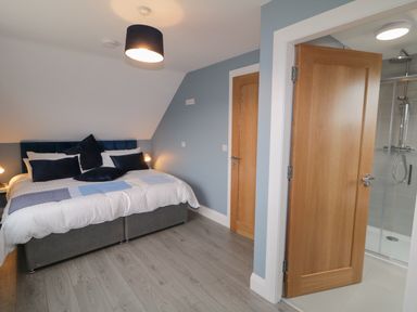 A bedroom with a double bed and pillows and an open door leading to a bathroom at ARD NA GHAOITHE in Loughanure County Donegal