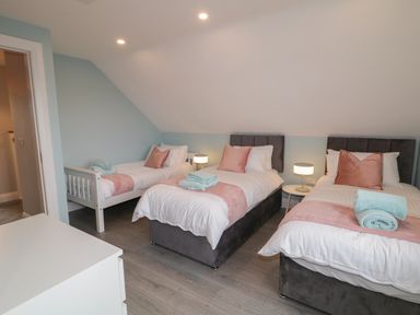 A bedroom with three single beds bedside tables lamps and folded towels at ARD NA GHAOITHE in Loughanure County Donegal