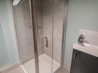 A shower enclosure with a glass door next to a sink with a soap dispenser at ARD NA GHAOITHE in Loughanure County Donegal