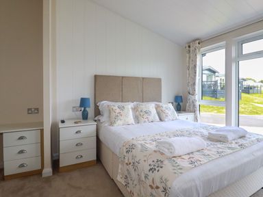 A bedroom with a bed with floral bedding and two bedside tables with blue lamps at 43 The Maples in Sticker