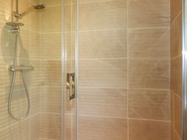 A shower area with a handheld showerhead and glass door at 43 The Maples in Sticker