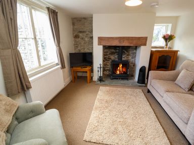 A sitting room with a fireplace armchair sofa television and a wooden cabinet at Holborn Cottage Blencathra Street Keswick