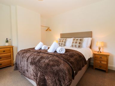 A bedroom with a bed covered by a brown blanket and white towels on a bed at Holborn Cottage Blencathra Street Keswick