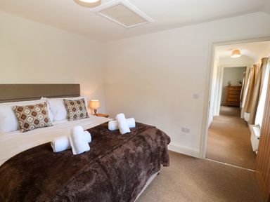 A bedroom with a bed and rolled towels next to a hallway at Holborn Cottage Blencathra Street Keswick