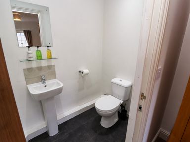 A small bathroom with a pedestal sink toilet and mirror at Holborn Cottage Blencathra Street Keswick
