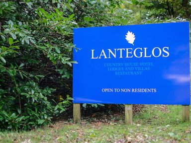 A blue sign for Lanteglos country house hotel lodges and villas restaurant surrounded by greenery at Lanteglos Holiday Park near Camelford
