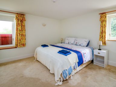 A bedroom with a double bed two windows yellow floral curtains and two bedside tables with lamps at West Dairy near Newport Pembrokeshire