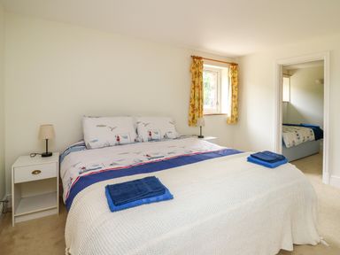 A bedroom with a double bed two bedside tables with lamps yellow floral curtains and a view into another bedroom at West Dairy near Newport Pembrokeshire